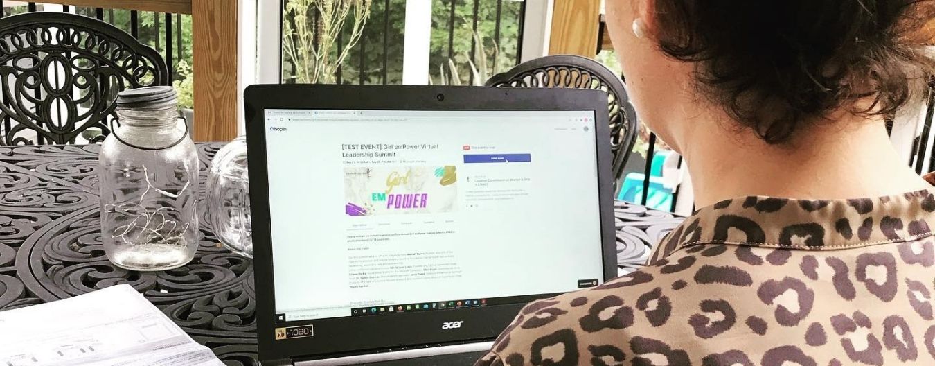 23 – LCWAG Loudoun 8th Grader Organizes Young Women’s Empowerment Summit Person using a laptop to view a virtual girls’ empowerment summit registration page while seated at an outdoor table.