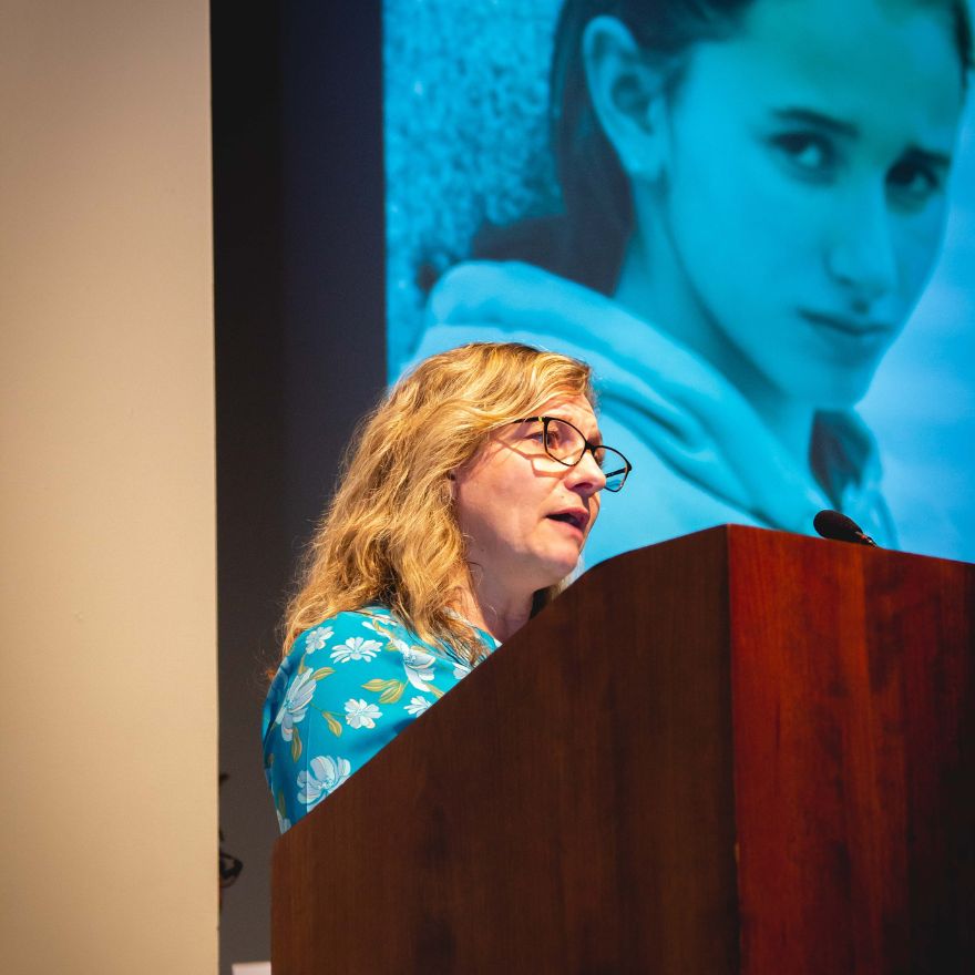 LCWAG Human Trafficking Seminar picture depicting a female speaker at the podium with a projected image of a young girl in distress in the background.
